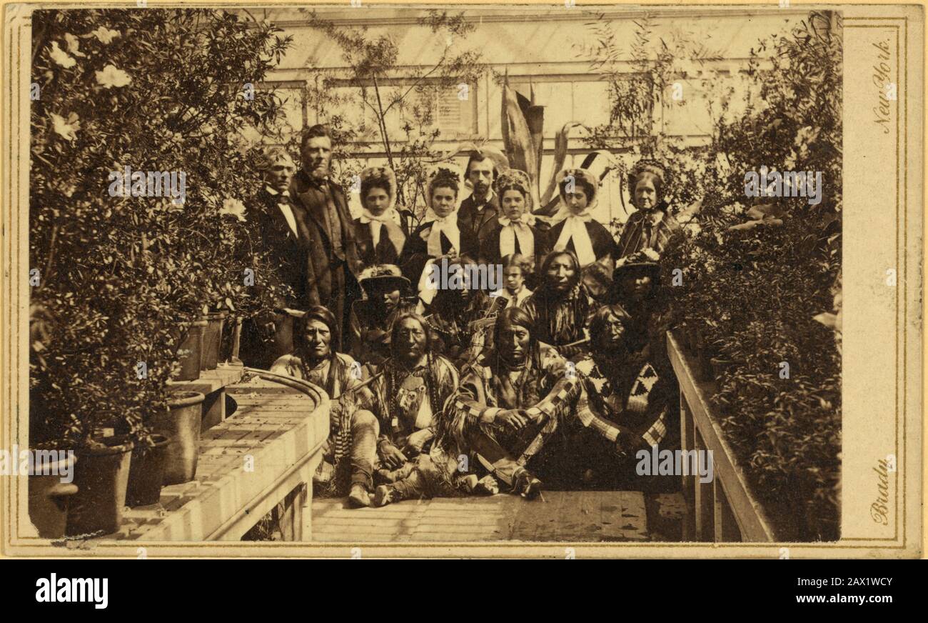 März, WASHINGTON, DC, USA: Indische Delegation im Weißen Haus Conservatory während des Bürgerkrieges, mit J.G. Nicolay, der Sekretär von Präsident Abraham Lincoln, steht in der hinteren Reihe des Zentrums. Der Präsident der USA, ABRAHAM LINCOLN (* 1809; † 1865). Foto der Southern Plains Delegation, aufgenommen am 27. März im White House Conservatory. Der Interpret William Simpson Smith und der Agent Samuel G. Colley stehen links der Gruppe; die ganz rechts stehende weiße Frau wird oft als Mary Todd Lincoln identifiziert. Die Inder in der ersten Reihe sind dem Seufzen überlassen Stockfoto