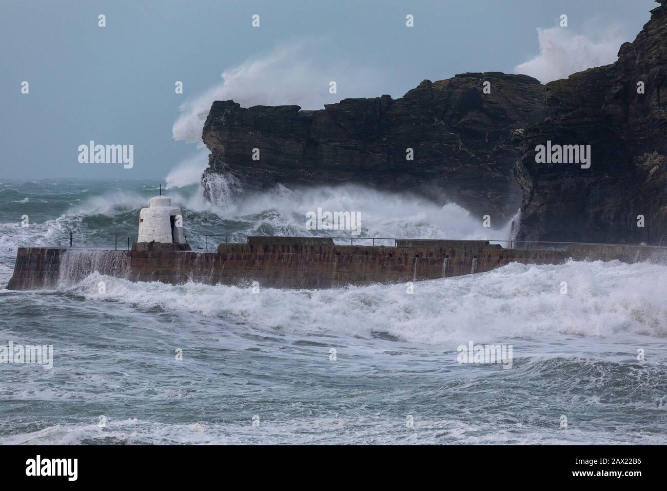 Storm Ciara schlägt die Küste von Cornwall mit riesigen Wellen, die so groß sind wie die umliegenden Klippen, die gegen das Wellenbrecher krachen Stockfoto