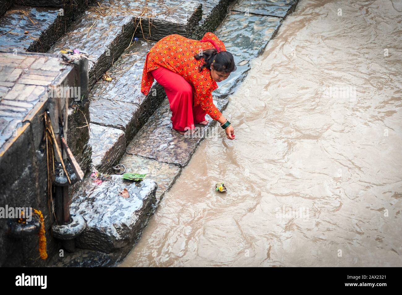 Unidentifizierte hinduistische Frau, von der man glaubt, dass sie ein heiligtes Bad im Bagmati-Fluss ist, um die Schuld zu waschen - am Pashupatinath-Tempel, einem Hindu-Tempel - Kathmandu Stockfoto