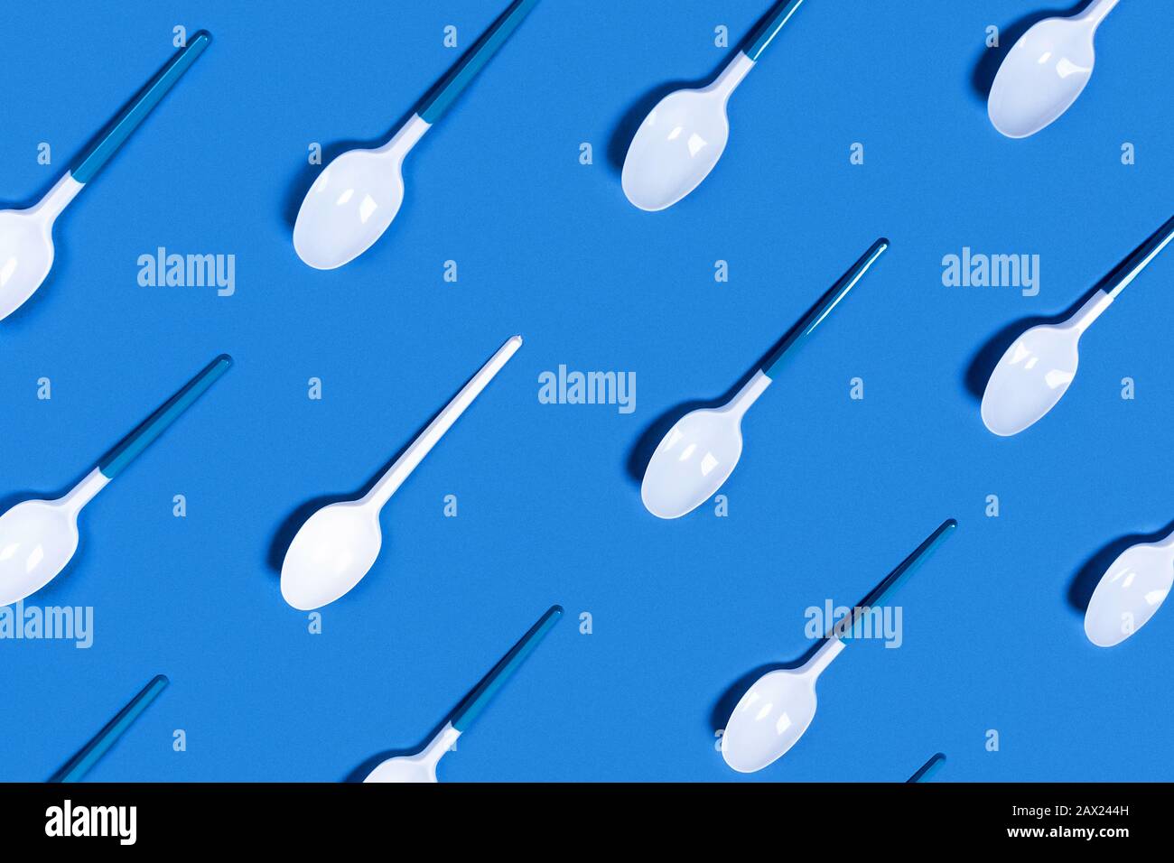 Abbildung der weißen Kunststofflöffel auf blauem Hintergrund. Flaches Layout, Draufsicht, Kopierbereich. Stockfoto