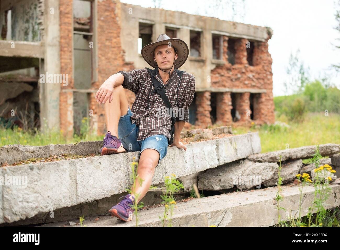 Ein Mann in einem Cowboyhut sitzt inmitten eines zerstörten Hauses. Stockfoto