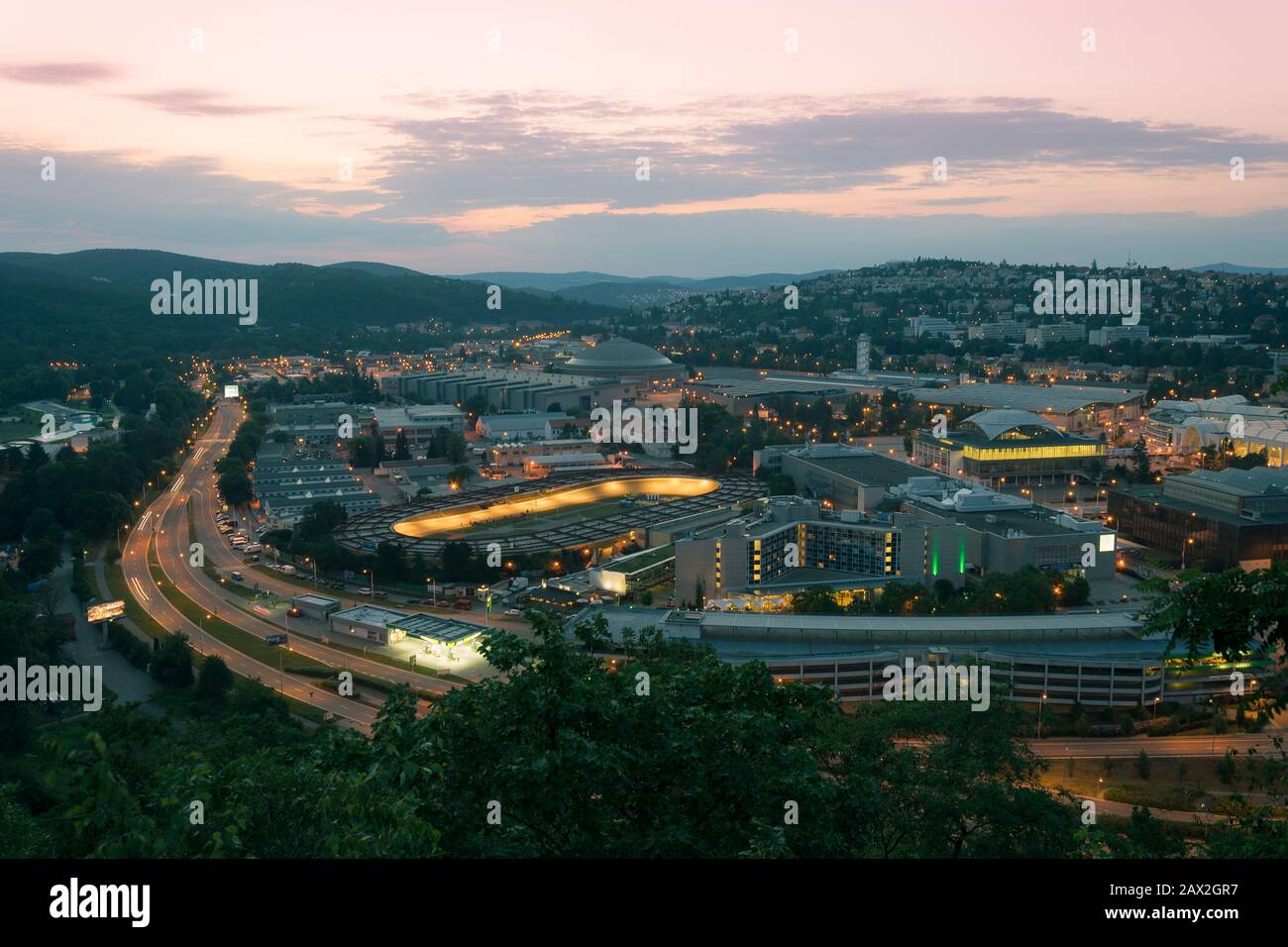 Leuchtende Dämmerung Brno Abend. Ausstellungszentrum, Velodrom, Straßenlaternen und Gebäude am frühen Abend des Sommers Foto von oben. Stockfoto