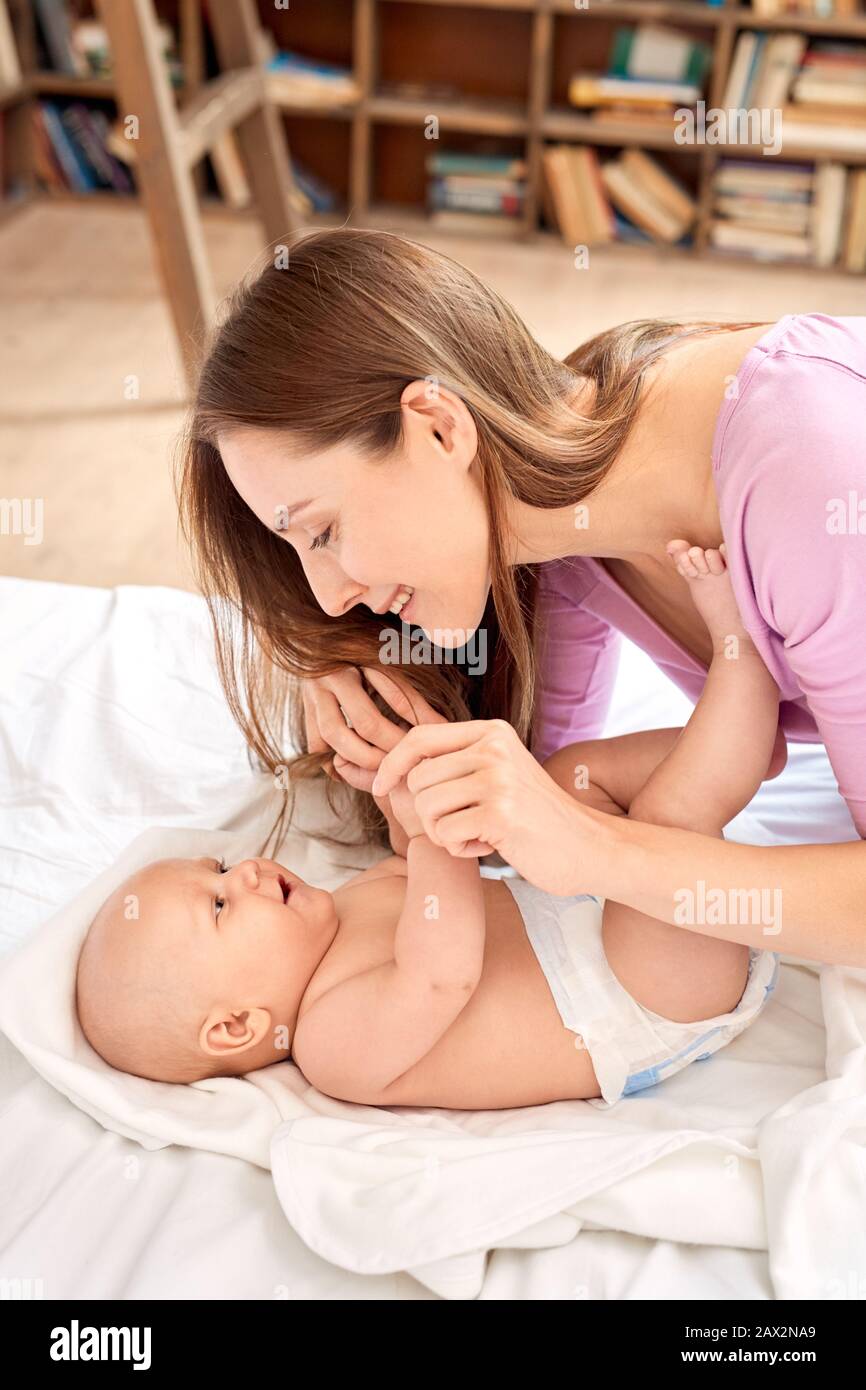 Junge Erwachsene Frau, die mit ihrem kleinen neugeborenen Baby spielt Stockfoto