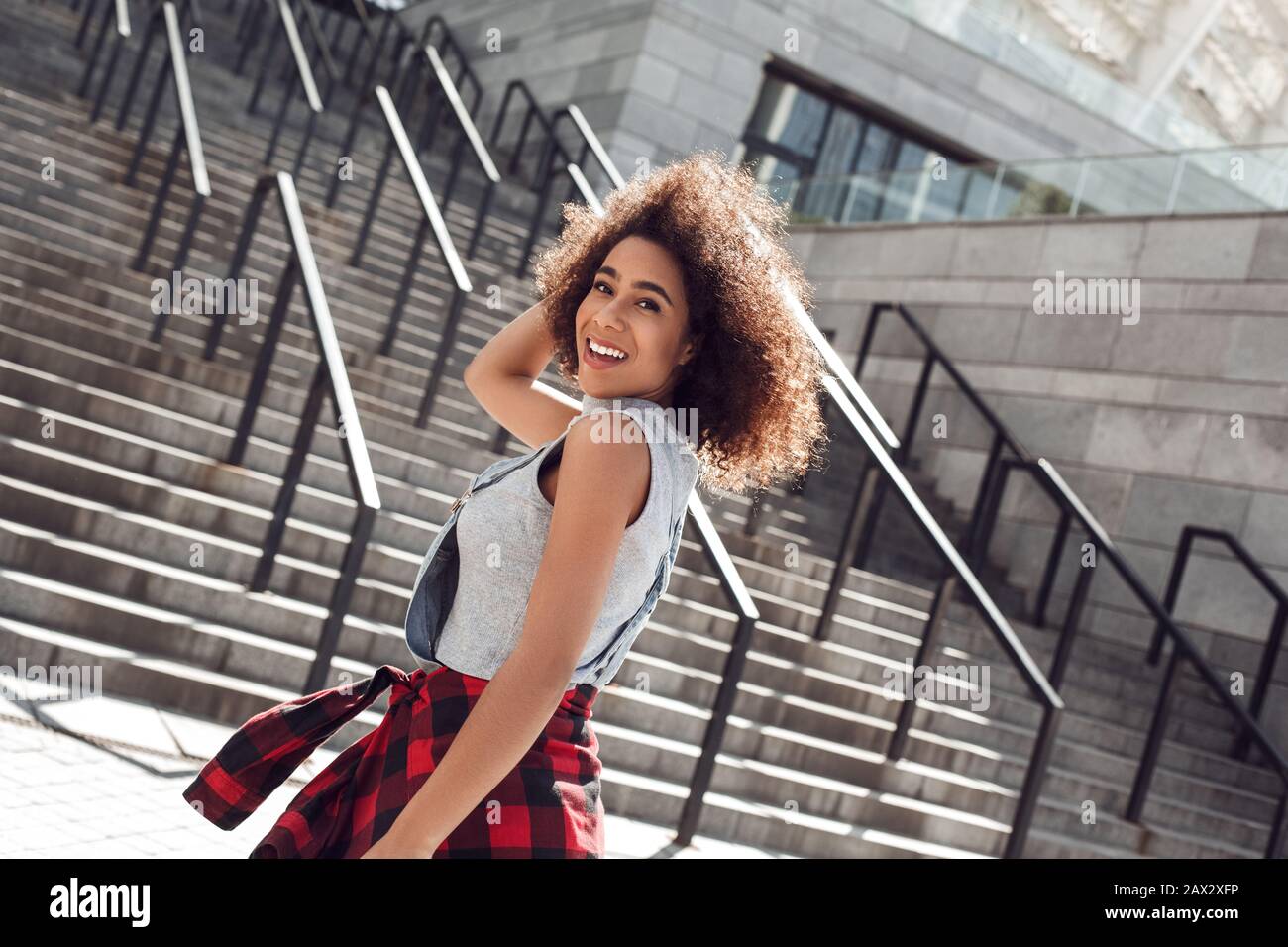 Junge Frau in der Stadtstraße lächelnd fröhlich auf einer Treppe stehend Stockfoto