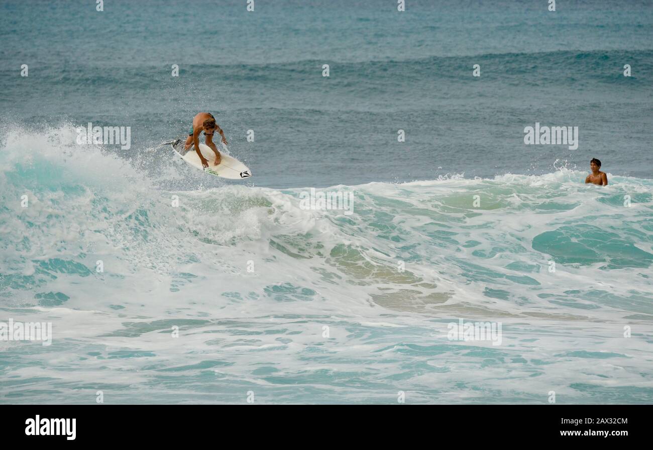 Männliche Surfer, die in Der Banzai-Pipeline an Nordufer, Oahu Island, Haleiwa, Hawaii, USA, mit weltweit bekannten, krachenden, geschwungenen türkisfarbenen Wellen reiten Stockfoto