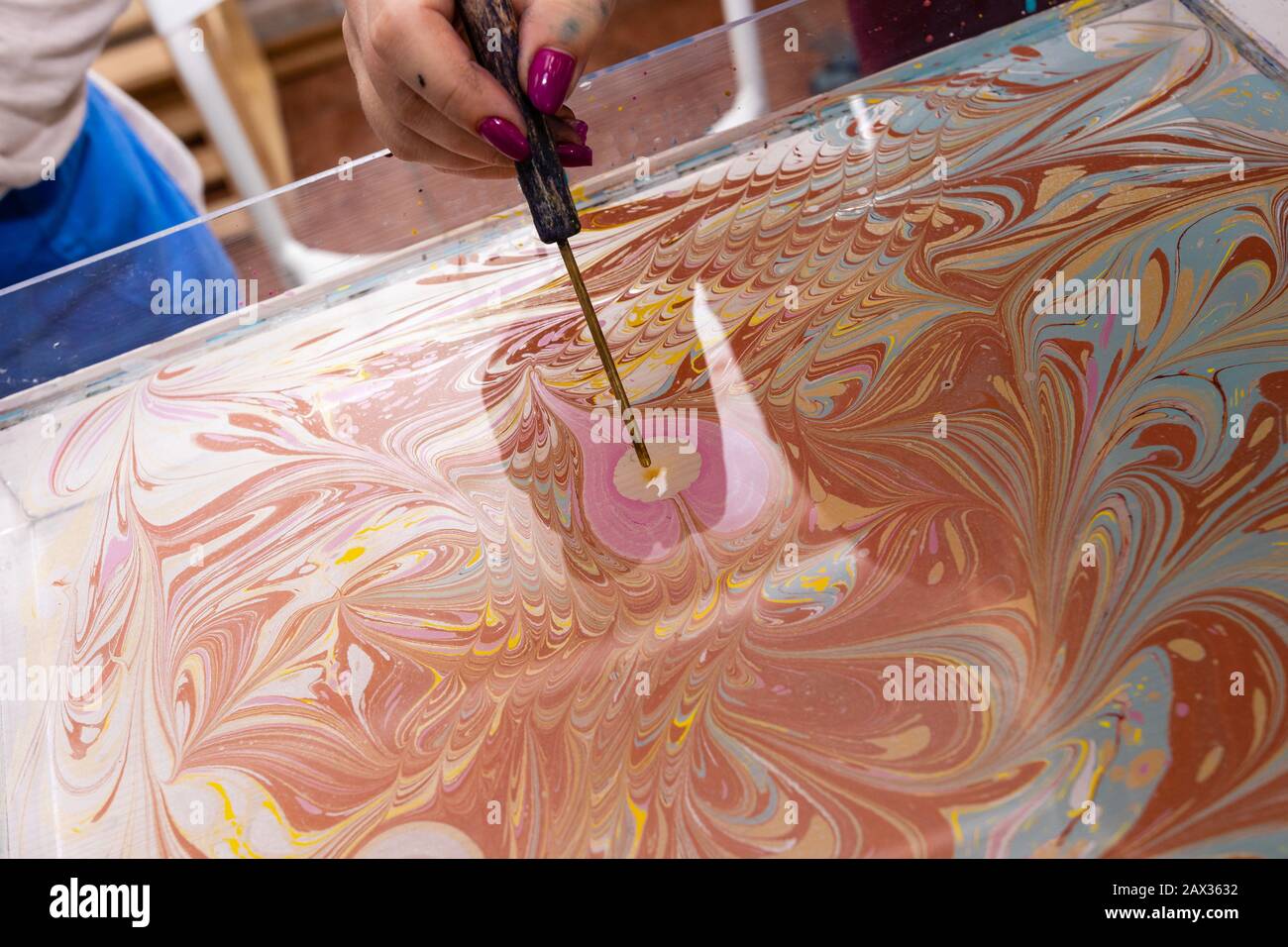 Meisterklasse im Atelier Ebru - die Kunst des "Malens auf dem Wasser." Frauenhände schließen sich. Stockfoto