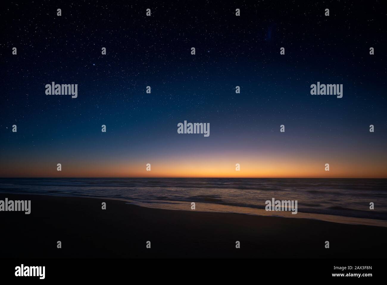 P Blick auf die Milchstraße, die über der Küstenlinie des Atlantiks verschwindet, während die Sonne auf der Südhalbkugel über den Horizont aufsteigt. Stockfoto