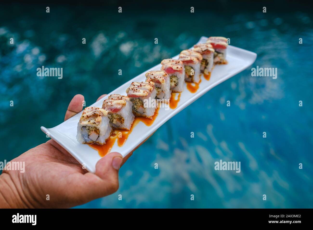 Halten Sie ein Tablett mit Sushi vor dem Pool Stockfoto