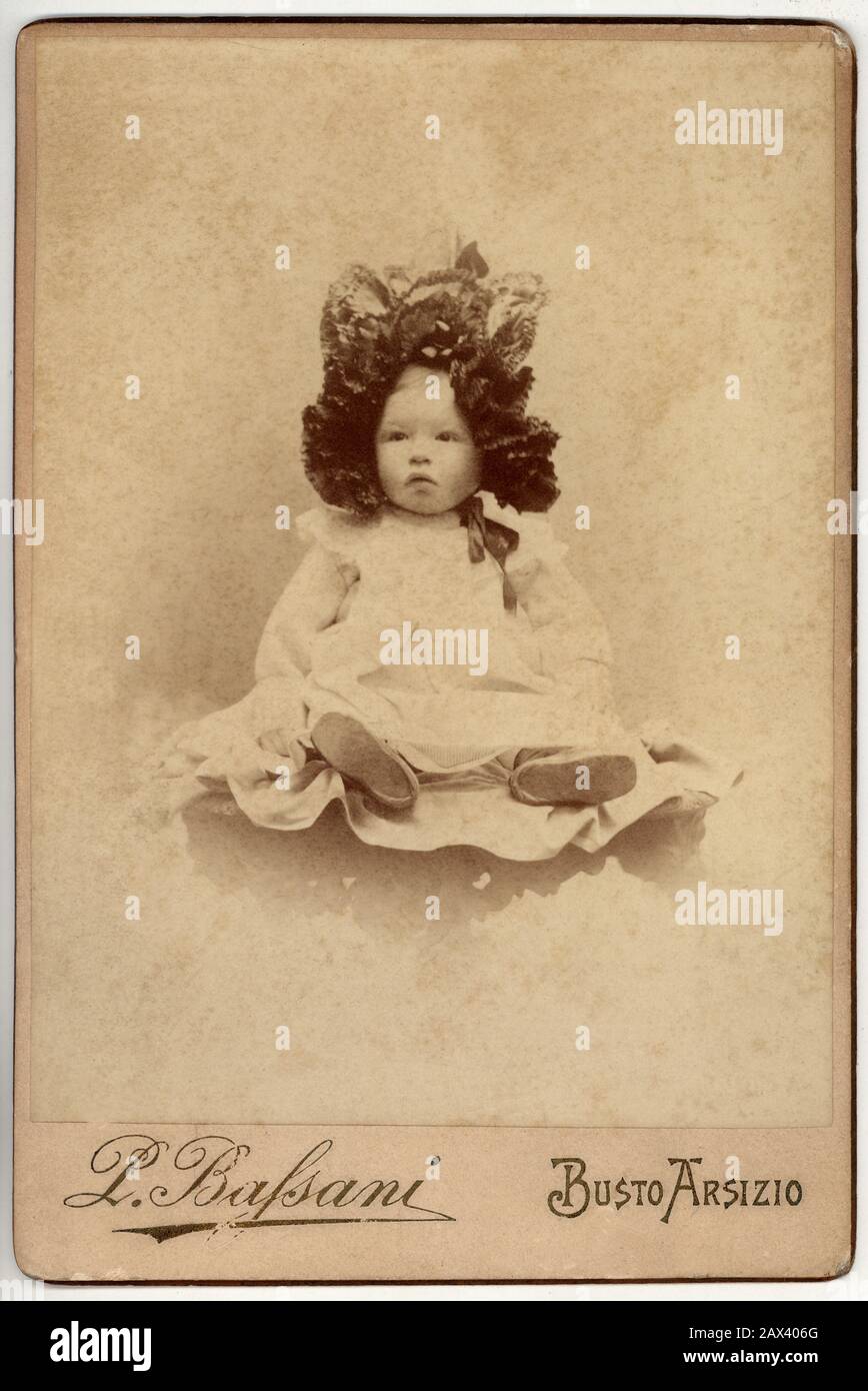 1890 Ca, ITALIEN: Kleines Mädchen ( oder Junge ) aus unberechtigter Adelsfamilie, die Motorhaube trägt. Foto von Pompeo Bassani , Busto Arsizio MILANO - FOTO STORICHE - HISTORIENFOTOS - BAMBINA - KIND - BAMBINO - BAMBINI - BAMBINE - KINDER - CUFIA - HUT - CAPPELLO - BÄNDER - NASTRI - NASTRO - TENEREZZA - ZÄRTLICH - SPITZE - KINDER - BAMBINA - BABY - OTTOCENTO - BELLE EPOQUE - FAMIGLIE Nobili ITALIANE - Nobiltà ITALIANA - ITALIENISCHER ADEL - MODE - MODA INFANTILE - BABY - bebé - weißes Kleid - abito vestito bianco ---- Archivio GBB Stockfoto