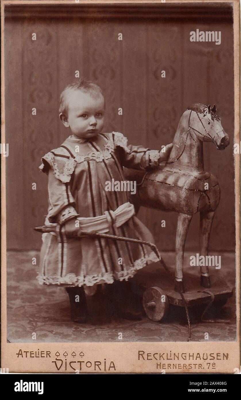 1890 Ca, DEUTSCHLAND: Kleiner Junge und Holzpferd. Foto von Atelier Victoria Recklinghausen - FOTO STORICHE - HISTORIENFOTOS - KIND - BAMBINO - BAMBINI - KINDER - Tenerezza - ZÄRTLICH - KINDER - BABY - OTTOCENTO - BELLE EPOQUE - MODE - MODA INFANTILE - BABY - Bebé - KINDHEIT - INFANZIA - Spielzeug - giocattolo - giocattoli - cavalluccio di Legno - Frusta WIMP - pizzo - Spitze - Archivio GBB Stockfoto