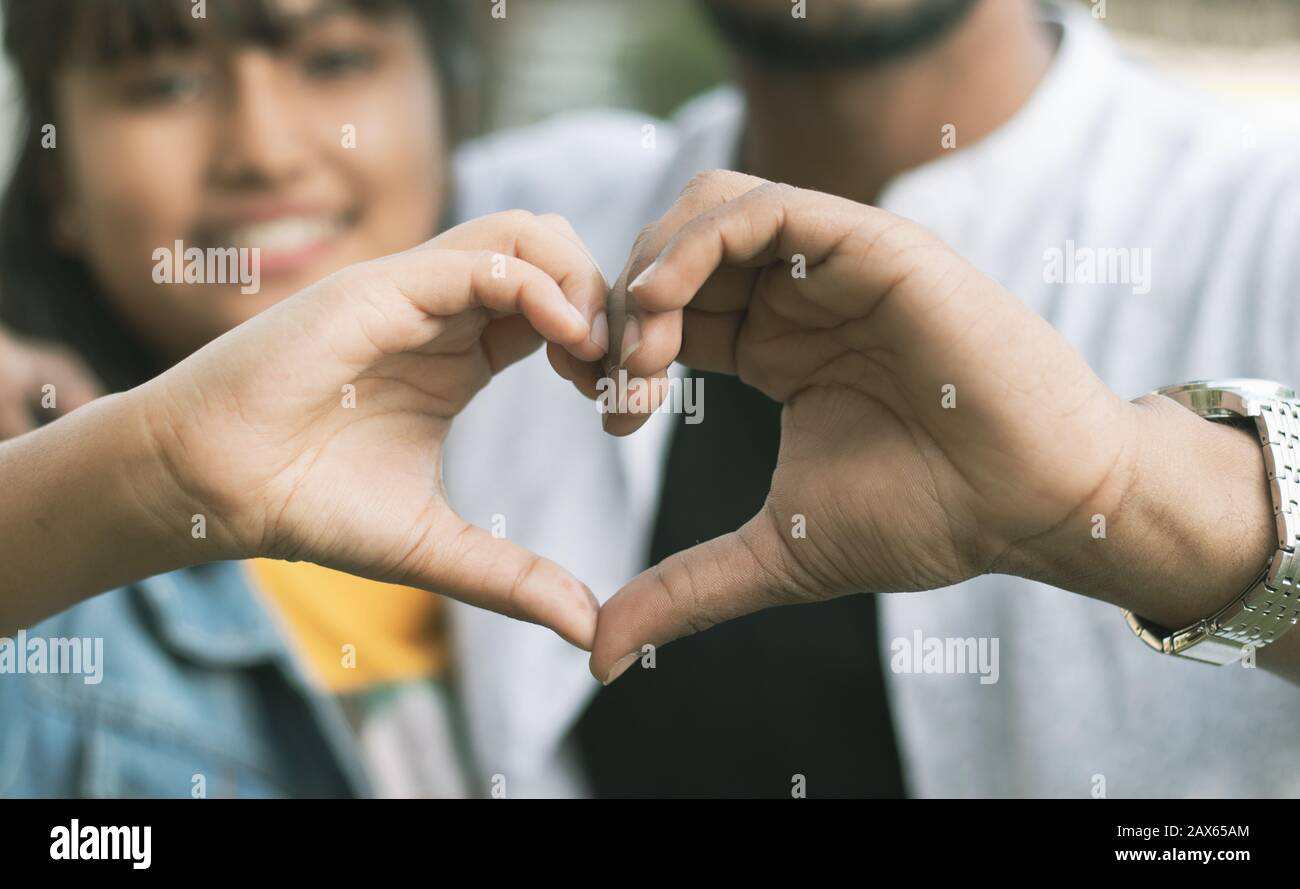 Ein Paar liebt es, Herz mit den Händen zu zeigen - Konzept der glücklichen Paarbeziehung und Zusammengehörigkeit Stockfoto