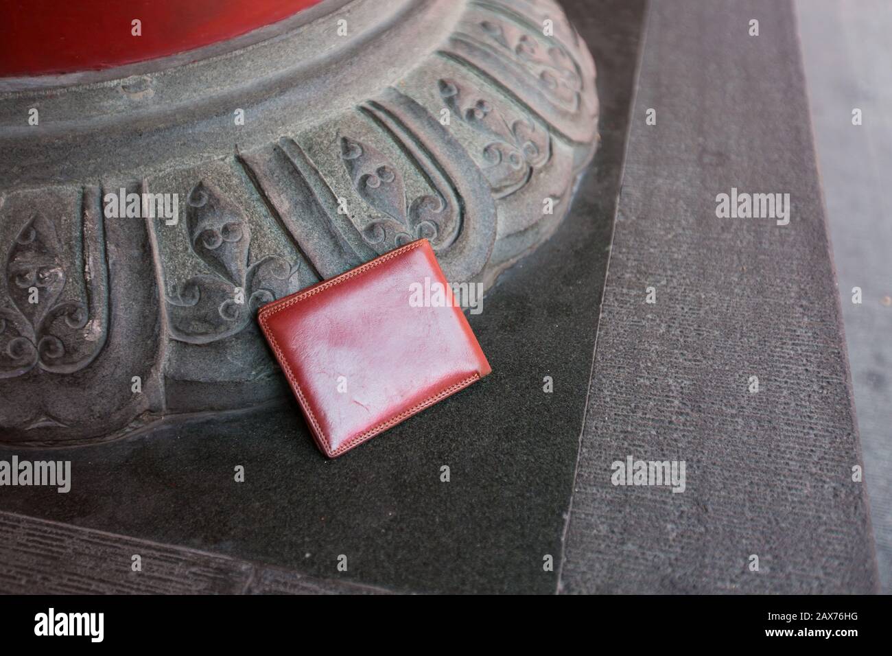Eine braune Brieftasche wurde unbeaufsichtigt in der Ecke eines öffentlichen Außenplatzes gefunden Stockfoto