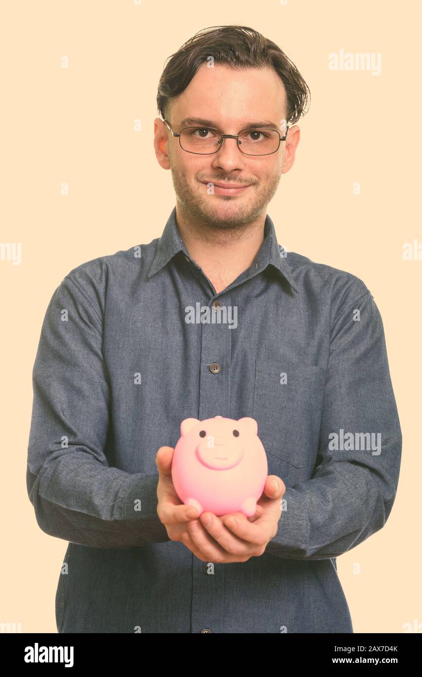 Studio shot der formalen junge Mann hält piggy Bank Stockfoto