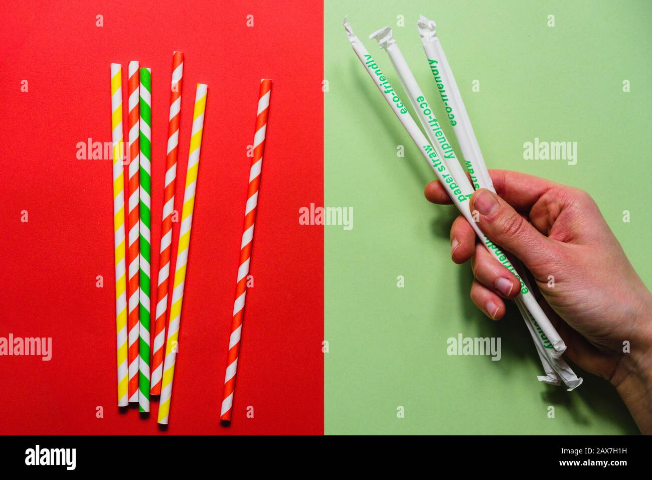 Papierstraten im Vergleich zu Kunststoff-Strohhalmen auf rotem und grünem Hintergrund Stockfoto