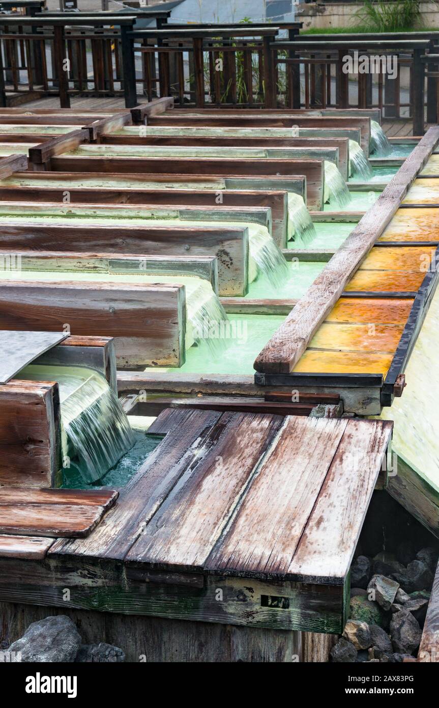 Mineralwasser, das über Holzkisten von Yubatake Onsen fließt, heiße Quelle. Kusatsu, Japan Stockfoto