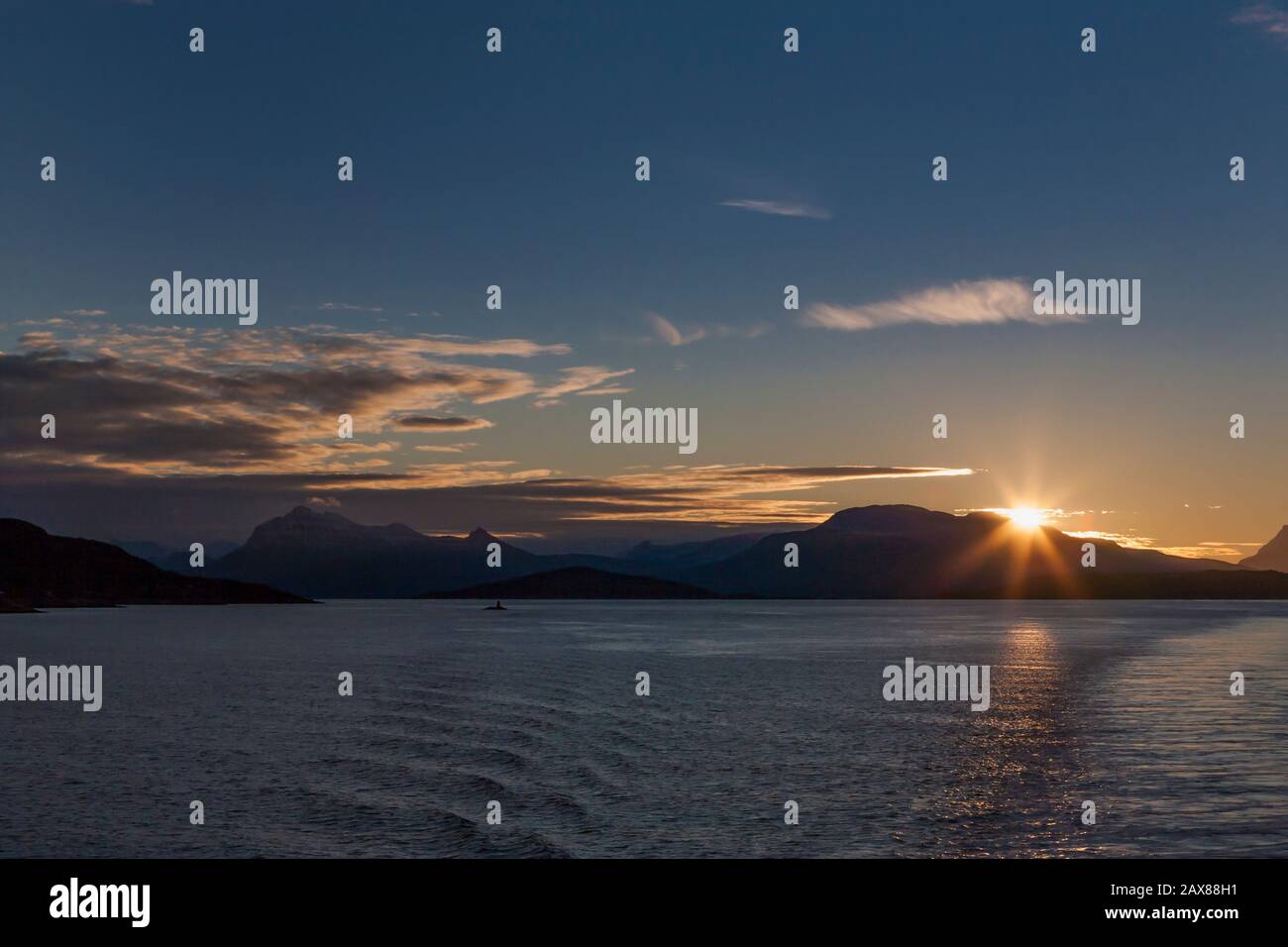 Am frühen Morgen scheint die Sonne über den Bergen der Insel Rolla, von Toppsundet, Troms og Finnmark, Nordnorwegen Stockfoto