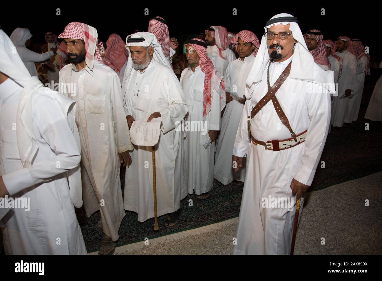 Hunderte saudi-arabische Männer warten darauf, entlassen zu werden, nachdem sie sich in seinem Wüstenlager außerhalb von Riad, Saudi-Arabien, zusammenfinden und eine Spende von Seinem Königlichen Hochglanzfürsten Al Waleed bin Talal Al-Saud erhalten haben. Stockfoto