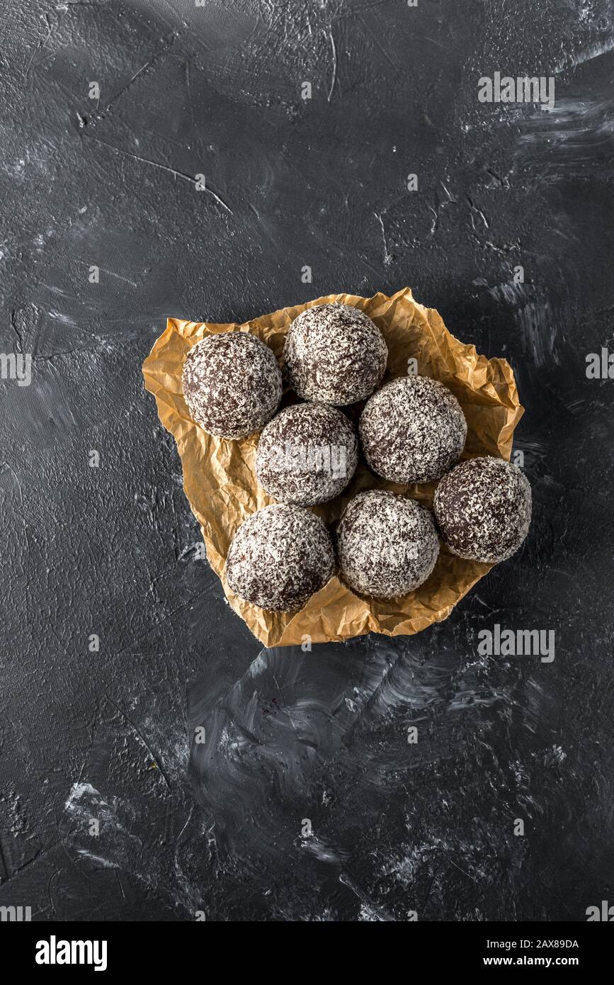 Hausgemachte gesunde Eiweißkugeln in einer Kokosschale mit getrockneten Aprikosen, Rosinen, Walnüssen, Mandeln und Kokosnuss. Gesundes süßes Essen Stockfoto