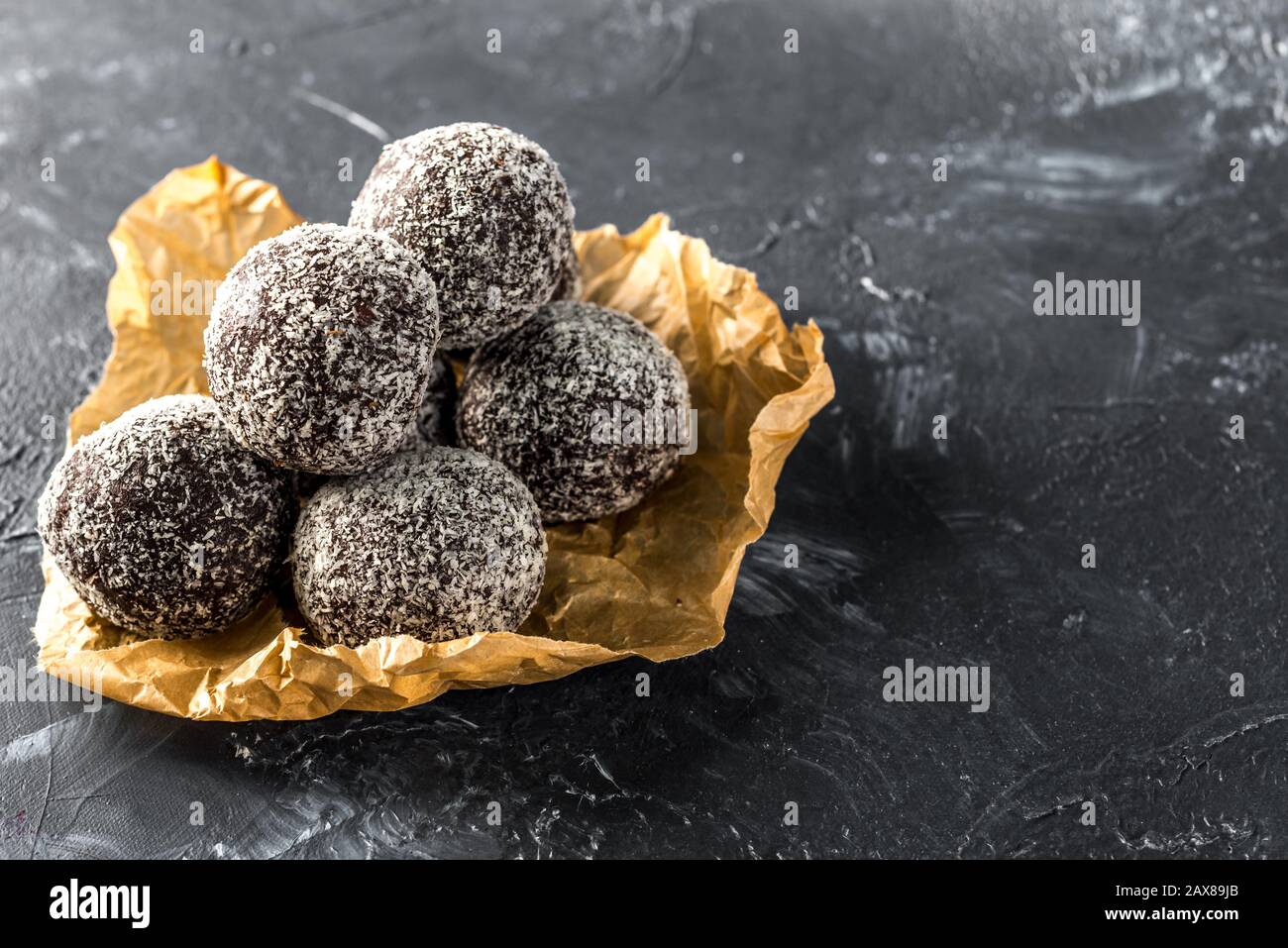 Hausgemachte gesunde Eiweißkugeln in einer Kokosschale mit getrockneten Aprikosen, Rosinen, Walnüssen, Mandeln und Kokosnuss. Gesundes süßes Essen Stockfoto