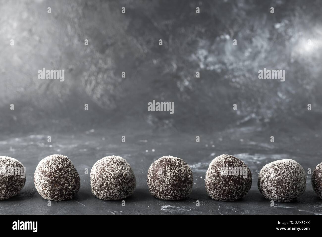 Hausgemachte gesunde Eiweißkugeln in einer Kokosschale mit getrockneten Aprikosen, Rosinen, Walnüssen, Mandeln und Kokosnuss. Gesundes süßes Essen Stockfoto