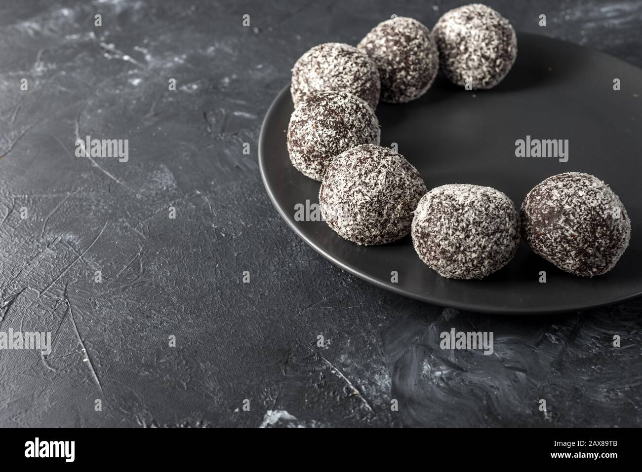 Hausgemachte gesunde Eiweißkugeln in einer Kokosschale mit getrockneten Aprikosen, Rosinen, Walnüssen, Mandeln und Kokosnuss. Gesundes süßes Essen Stockfoto