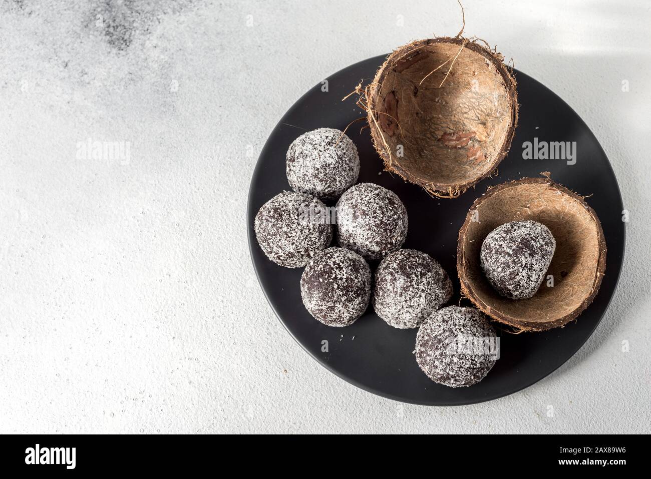 Hausgemachte gesunde Eiweißkugeln in einer Kokosschale mit getrockneten Aprikosen, Rosinen, Walnüssen, Mandeln und Kokosnuss. Gesundes süßes Essen Stockfoto