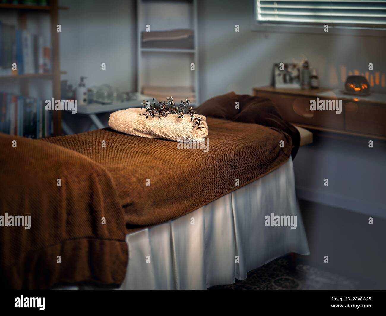 Massagetisch mit Handtüchern und Kerze in einem Schrank. Stockfoto