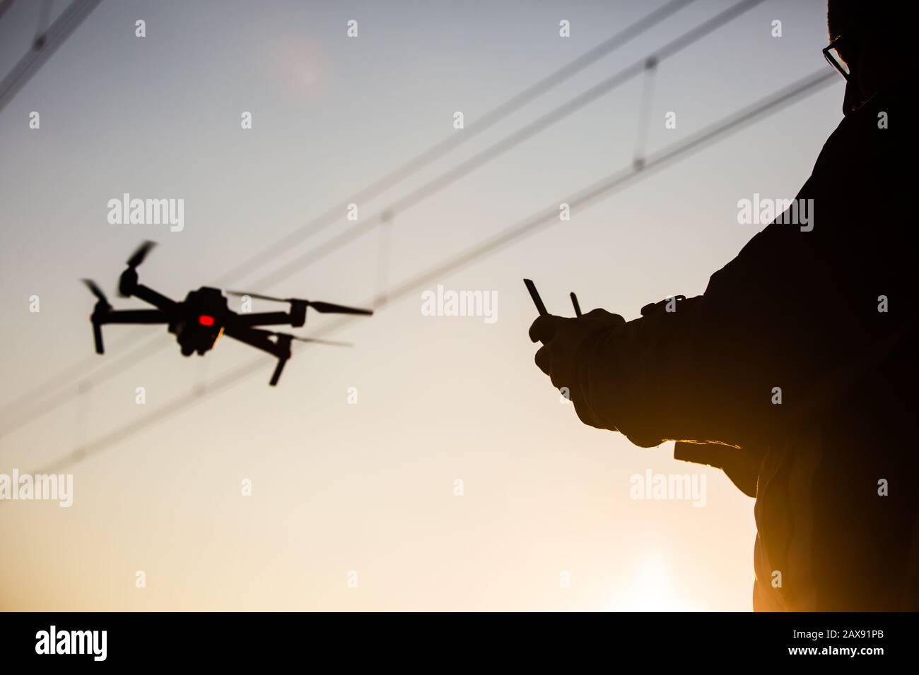 Mann, der die Drohne in der Nähe des elektrischen Kabels betreibt/Mann, der  die Drohnen/Drohnenregler der Fernbedienung hält Stockfotografie - Alamy