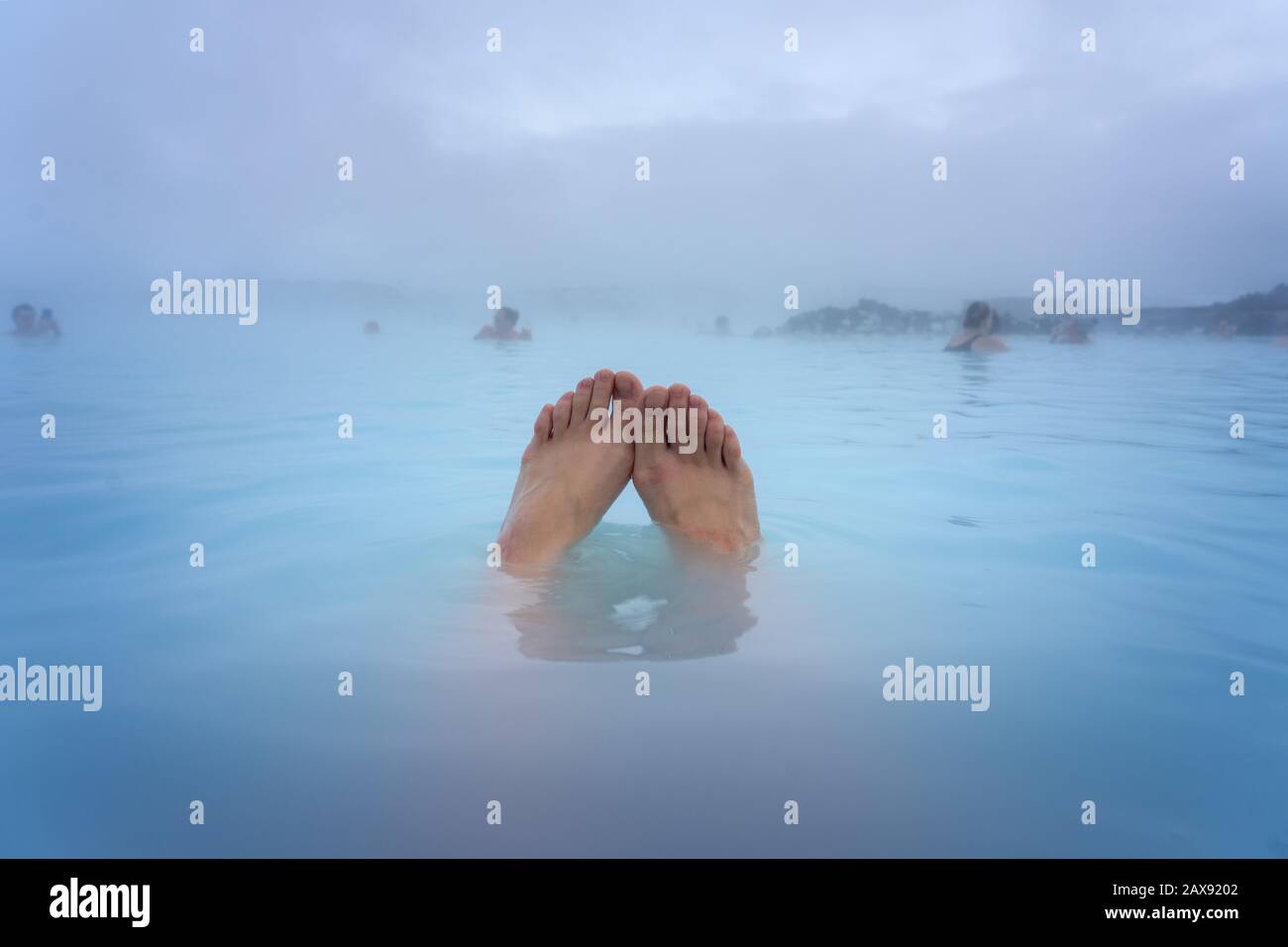 Füße einer Frau, die in der Blauen Lagune neben Reykjavik baden und in diesem natürlichen heißen Frühling baden Stockfoto