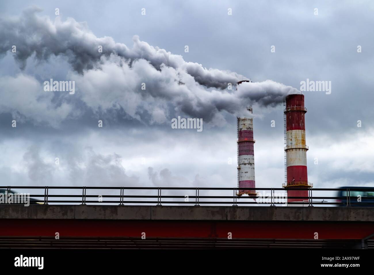 Dunkle giftige Rauchwolken, die über dem Autoverkehr aus dem Fabrikschornstein kommen. Luftverschmutzung und Erderwärmung durch altes Industriekraftwerk Stockfoto