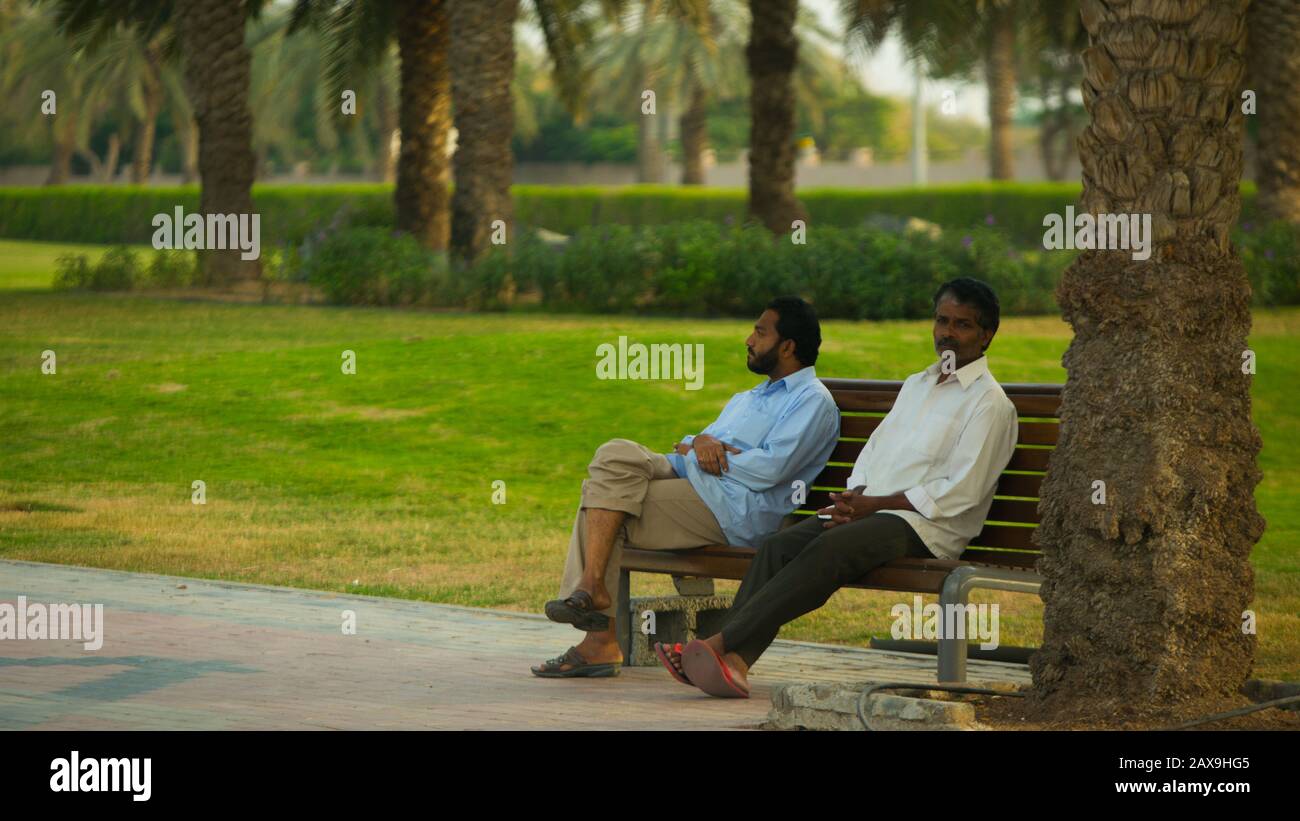 Indische Männer entspannen sich in einem Park in Dubai, Vereinigte Arabische Emirate. Stockfoto