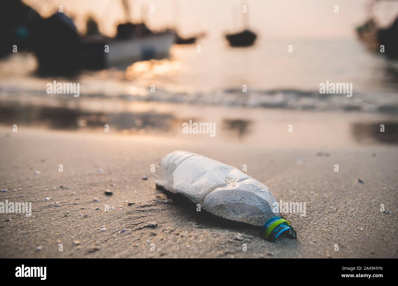 Plastikflasche am Strand mit Sonneneinstrahlung im Freien, wenig Licht und dunklem Schatten. Stockfoto