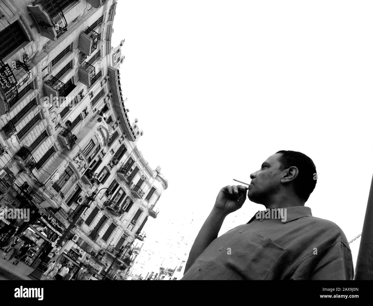 Der altägyptische Autor des Yacoubian Building, Alaa Al Aswany, pausiert für eine Zigarette auf der Straße Suleiman Basha (Talat Haarb), wo der größte Teil seines Romans am Freitag, den 25. August 2006 in der Innenstadt von Kairo steht. Das Yacoubian Building, ein kontroverser Roman, der Ägypten im Sturm mit seiner offenen Behandlung von Homosexualität und Kritik an der Regierung gebracht hat, wurde zu einem Film, der im Juli 2006 in Kairo veröffentlicht wurde. Aswany gilt vielen als der neue Naguib Mahfouz. Stockfoto