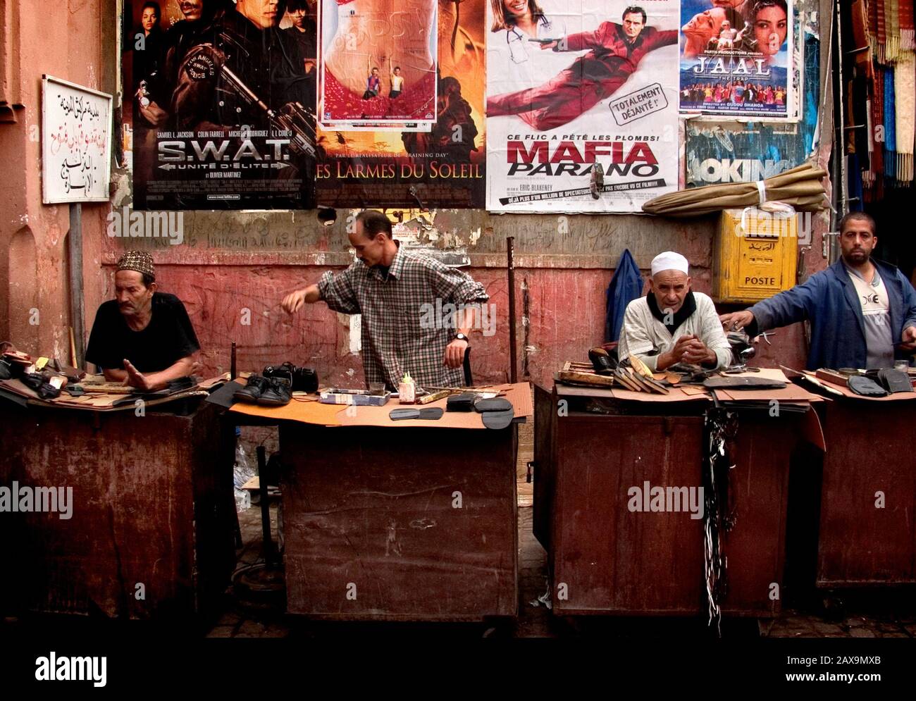 Straßencobbler mit Kulisse von Filmplakaten, Marrakesch, Marokko. Stockfoto