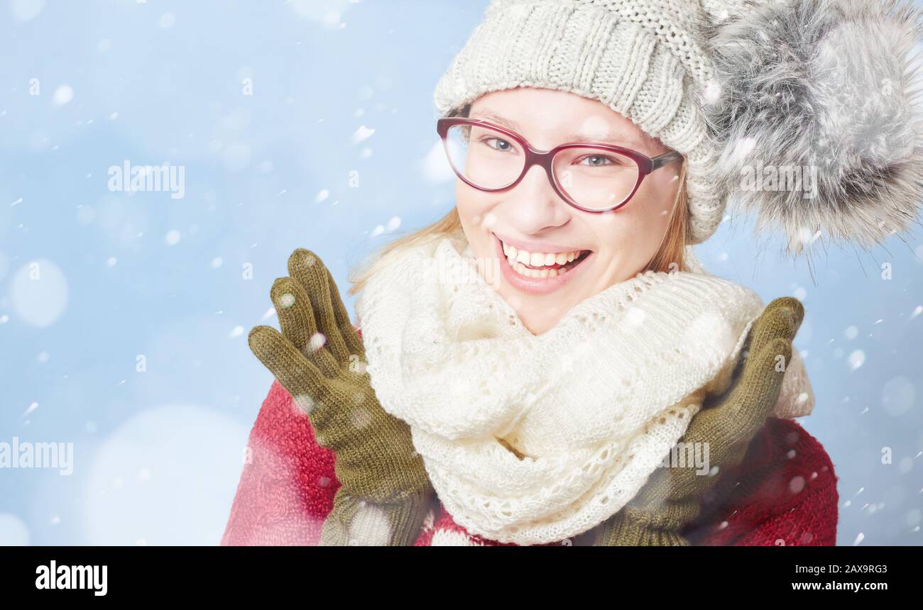 Lächelnde junge Frau im Winter im Schnee mit Hut und Schal Stockfoto