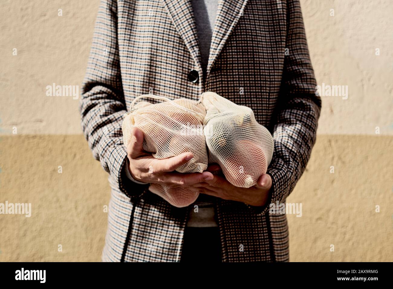 Nahaufnahme eines Mannes auf der Straße, der einige wiederverwendbare Textil-Netztaschen trug, früher zum Kauf von Lebensmitteln in loser Schüttung, voller Obst und Gemüse, als Maßnahme zu Stockfoto
