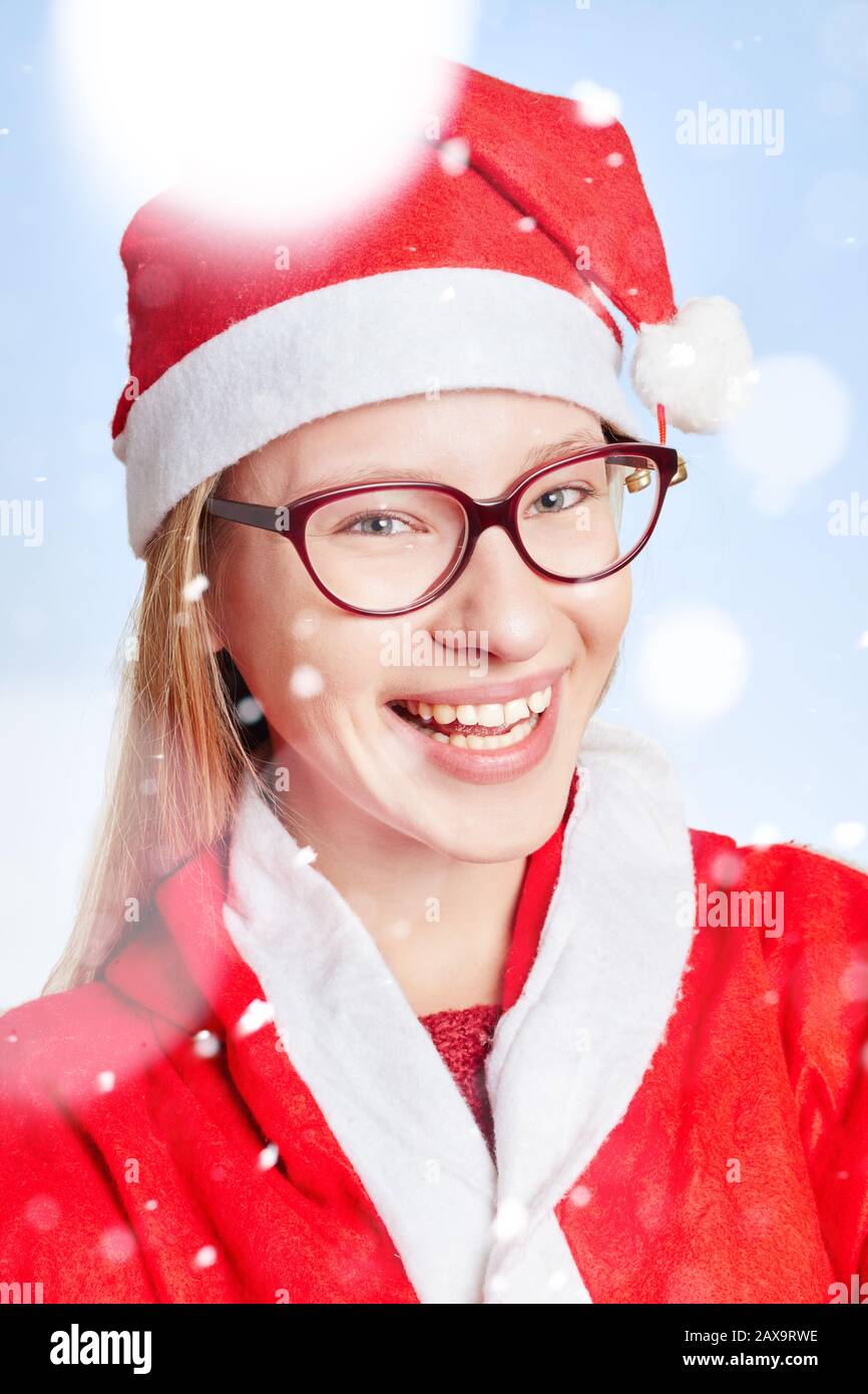 Lachende junge Frau als Weihnachtsmann mit Hut im Schnee Stockfoto