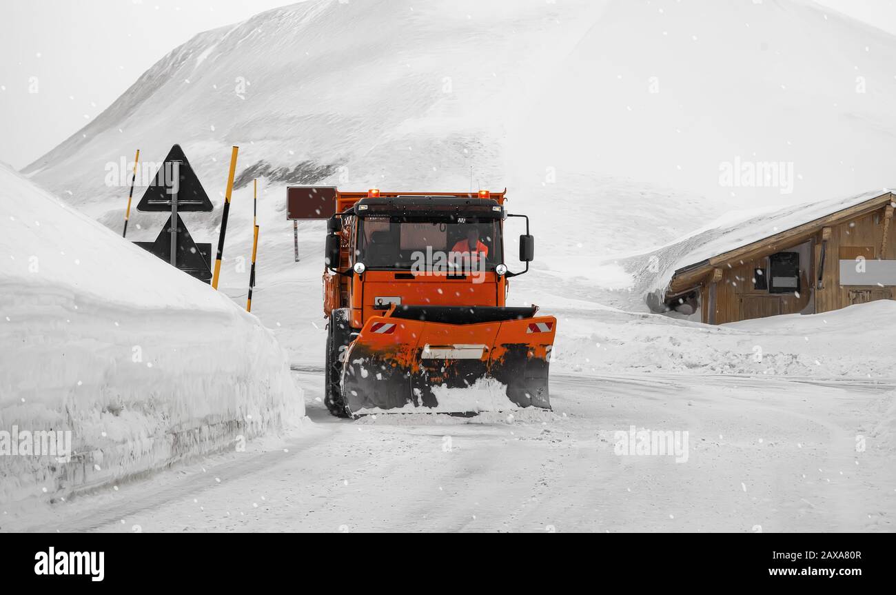Vorderansicht des Schneepflugwagens bei der Arbeit an einem stürmischen Wintertag in den alpen. Stockfoto