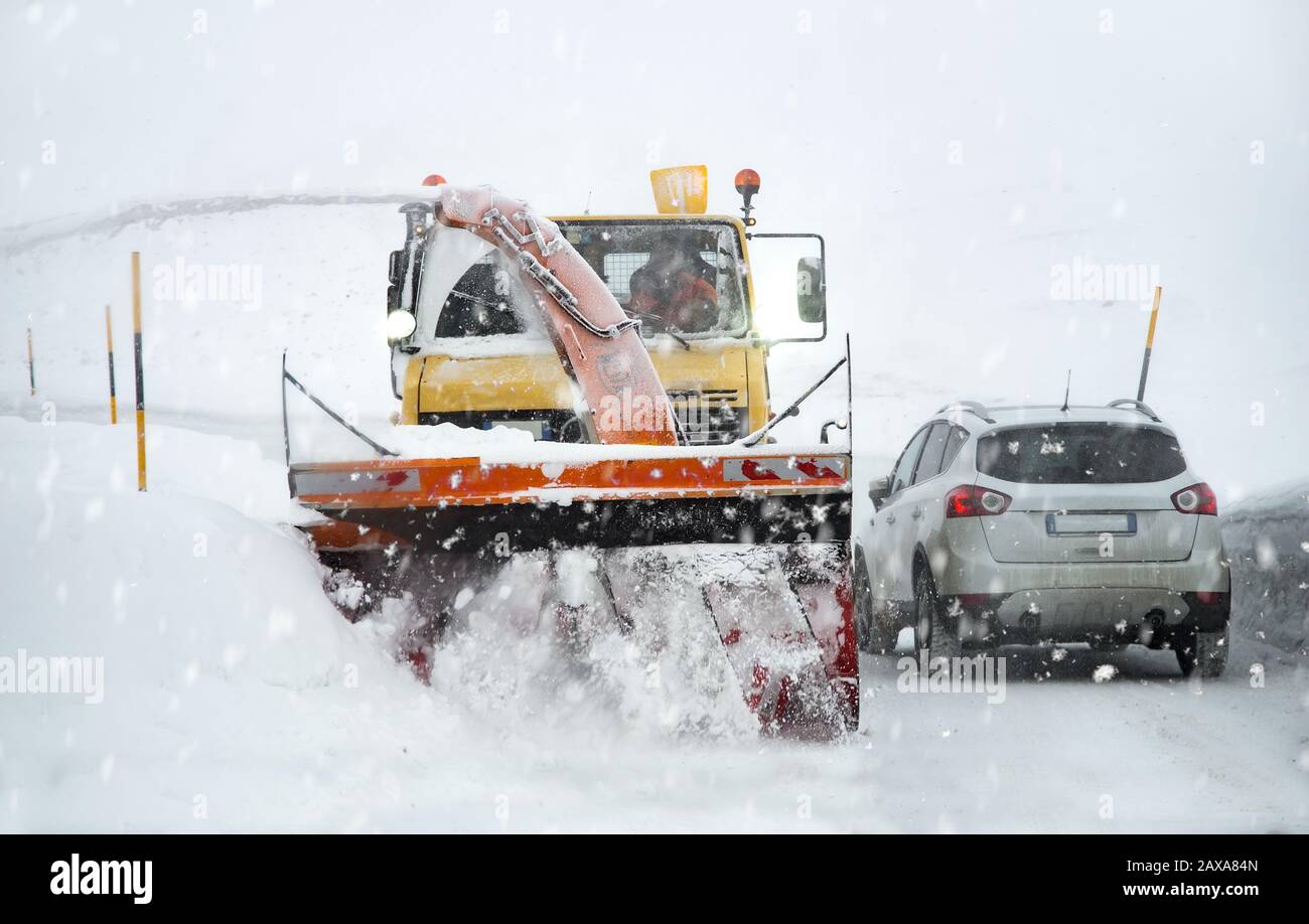 Vorderansicht des Schneepflugwagens bei der Arbeit an einem stürmischen Wintertag in den alpen. Stockfoto