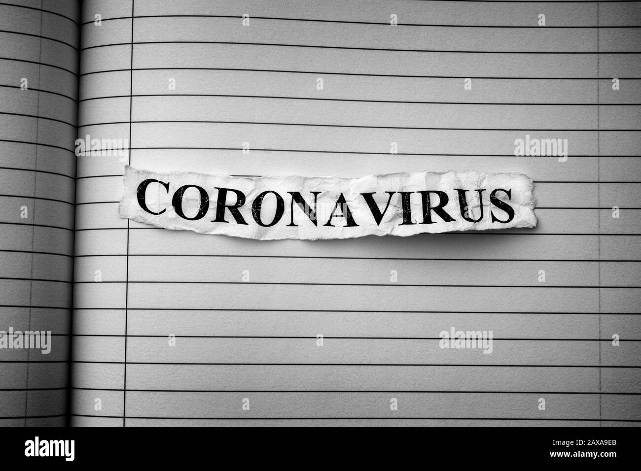Streifen der Zeitung mit dem Wort Coronavirus darauf tippte. Schwarzweiß. Nahaufnahme. Stockfoto