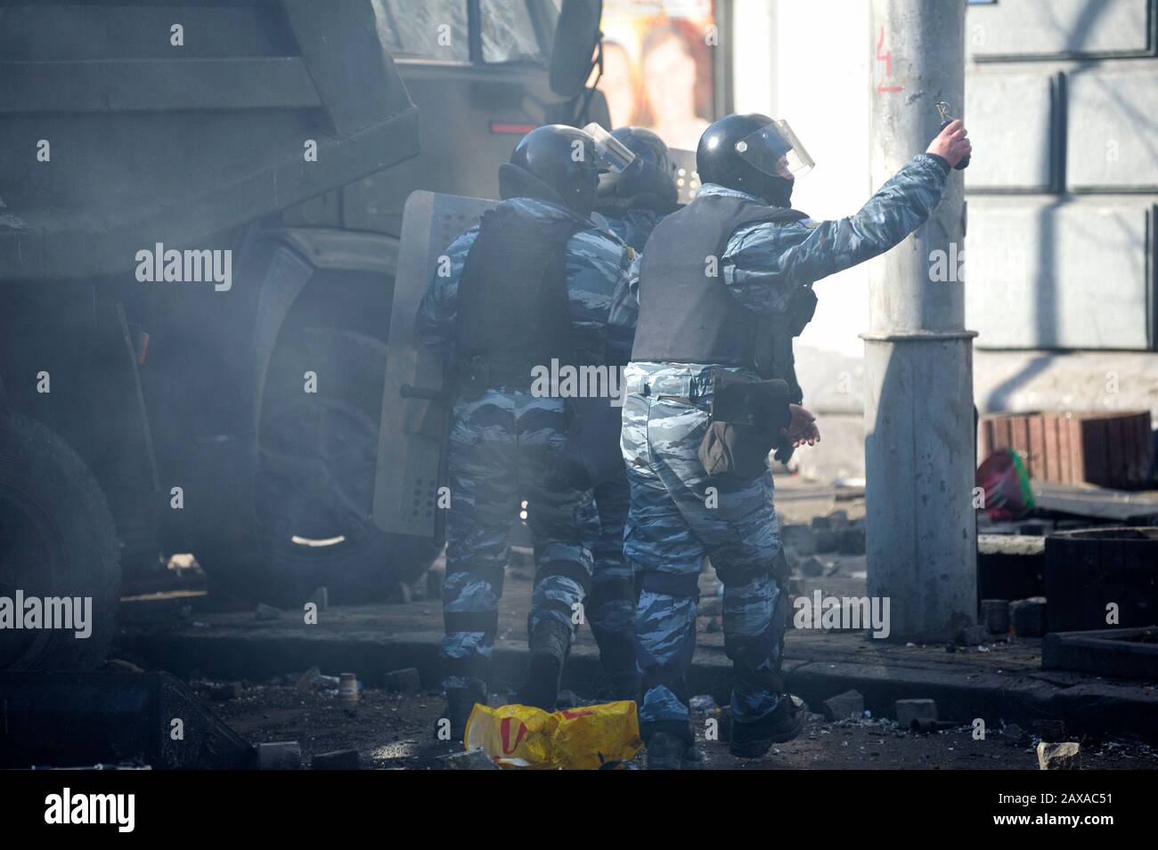 Polizei greift an: Polizist (Berkut) hält eine Granate vor einer Barrikade. Revolution der Würde. Februar 2014. Kiew, Ukraine Stockfoto