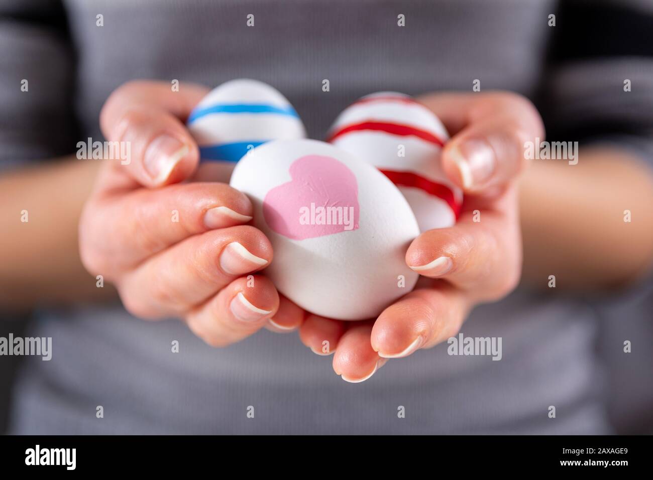Mädchen Hände mit Ostern bunten Eiern. Mädchen, die eine Gruppe von Eiern in den Händen halten. Osterferienkonzept. Nahaufnahme, selektiver Fokus Stockfoto
