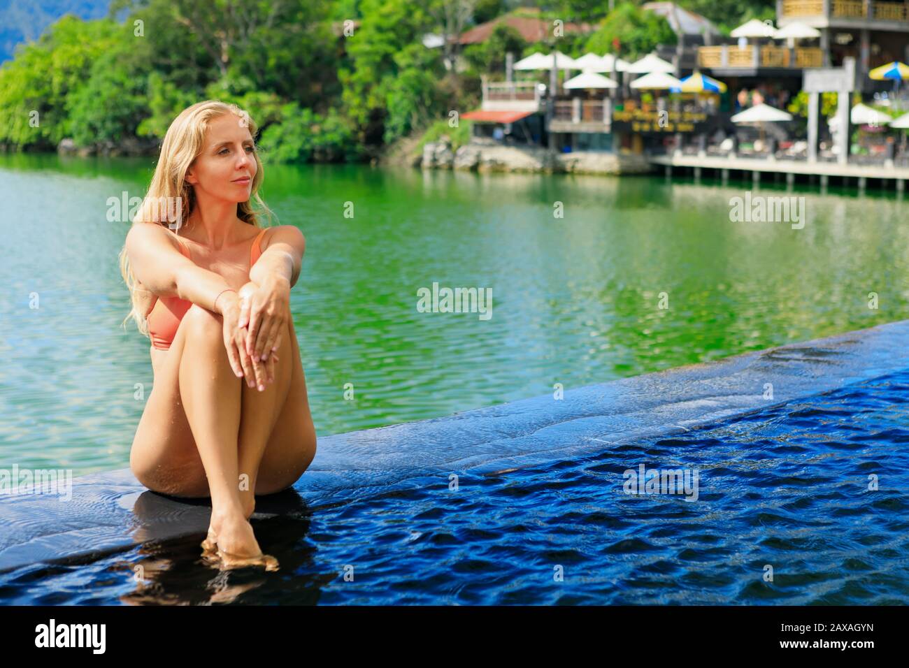 Junge Frau entspannen im Infinity-Pool mit Blick auf den See. Thermalbad unter dem Vulkan Batur. Reisen Sie in Kintamani, Bali. Gesunder Lebensstil, Nachbildung Stockfoto