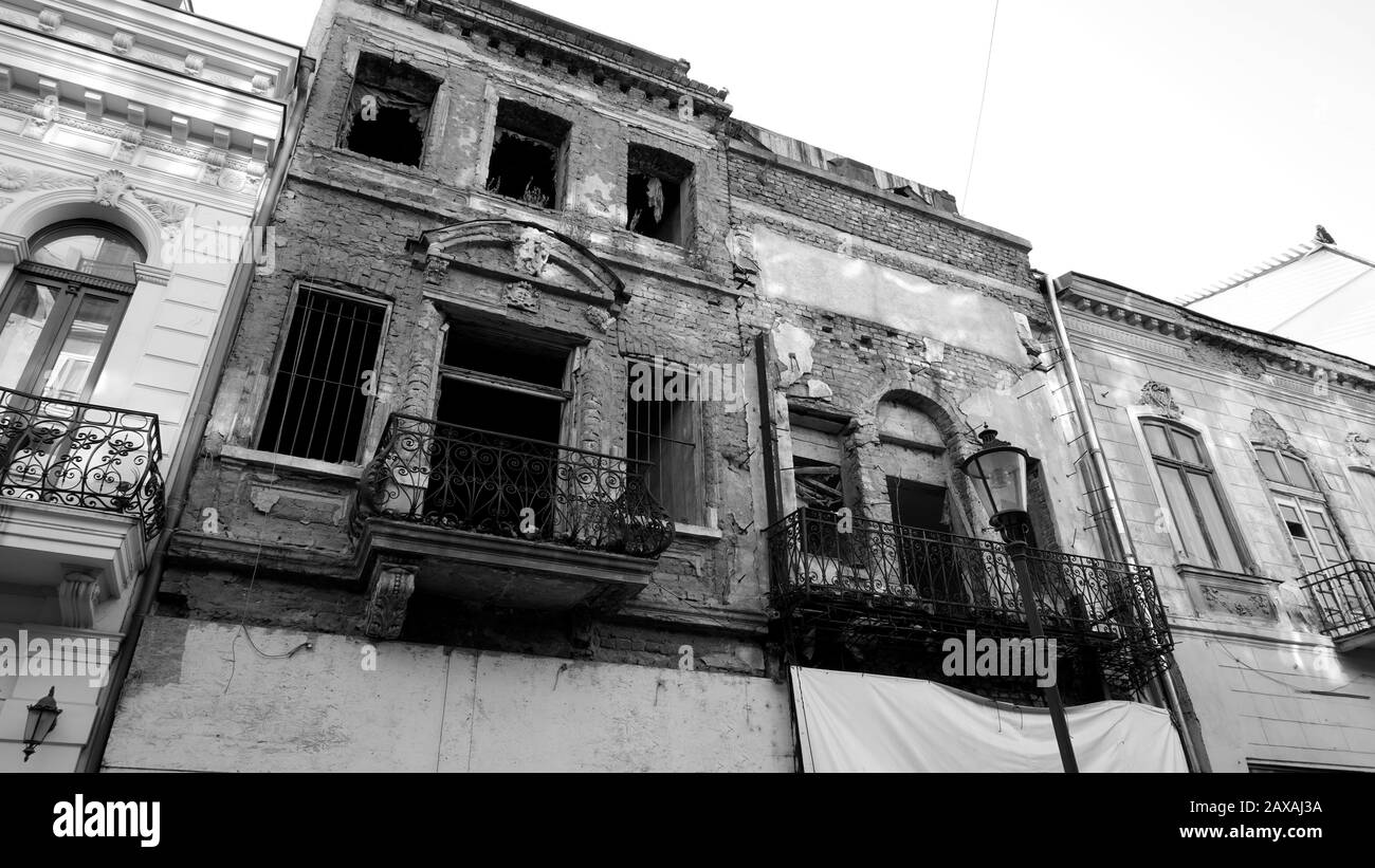 Fassade eines sehr alten Ziegelhauses oder Gebäudes verfiel und war in der Ruine. Beschädigte oder zerstörte Wohnung oder Gebäude ohne Fenster. Schwarzweißfotografie Stockfoto