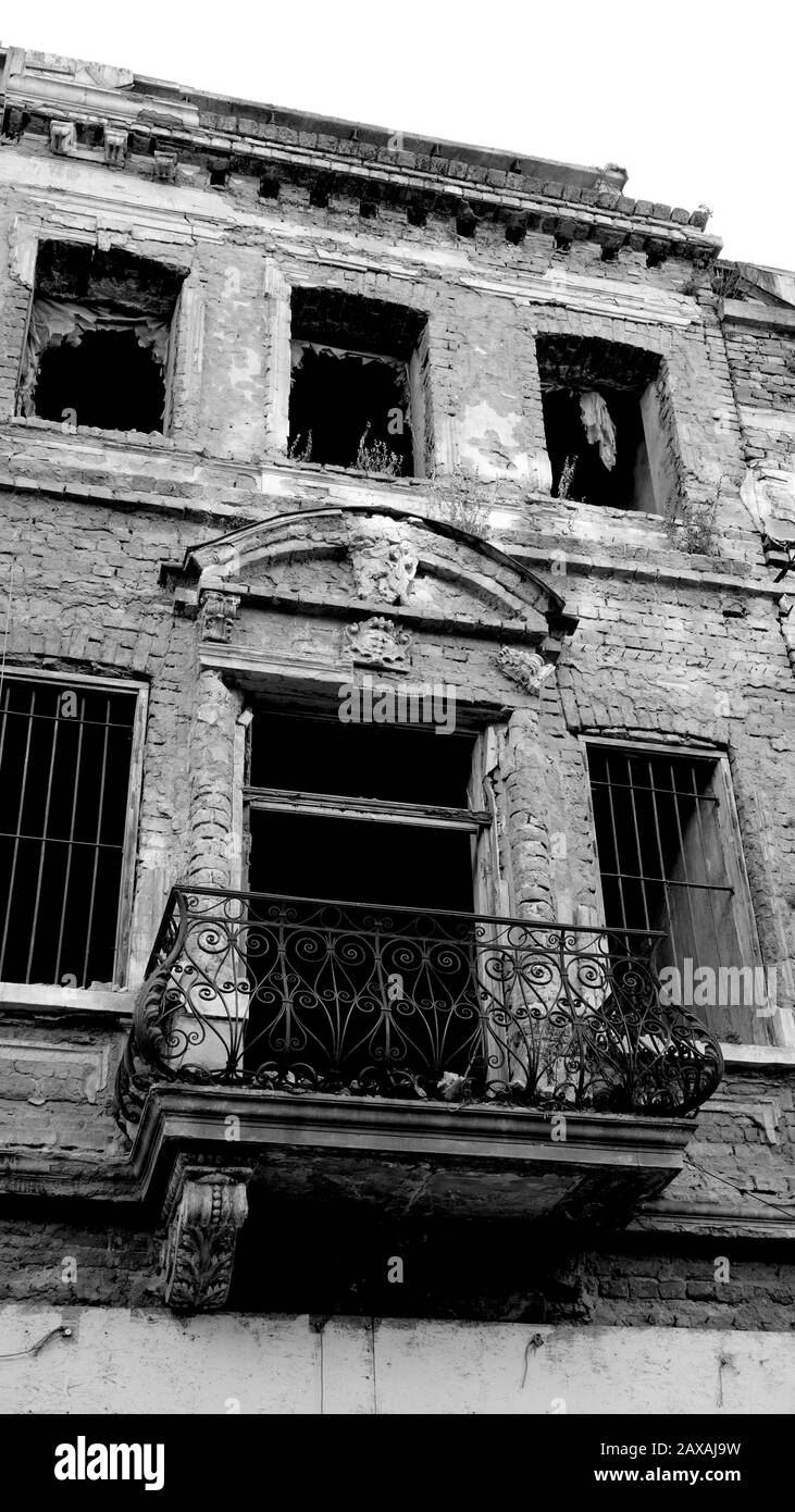 Fassade eines sehr alten Ziegelhauses oder Gebäudes verfiel und war in der Ruine. Beschädigte oder zerstörte Wohnung oder Gebäude ohne Fenster. Schwarzweißfotografie Stockfoto