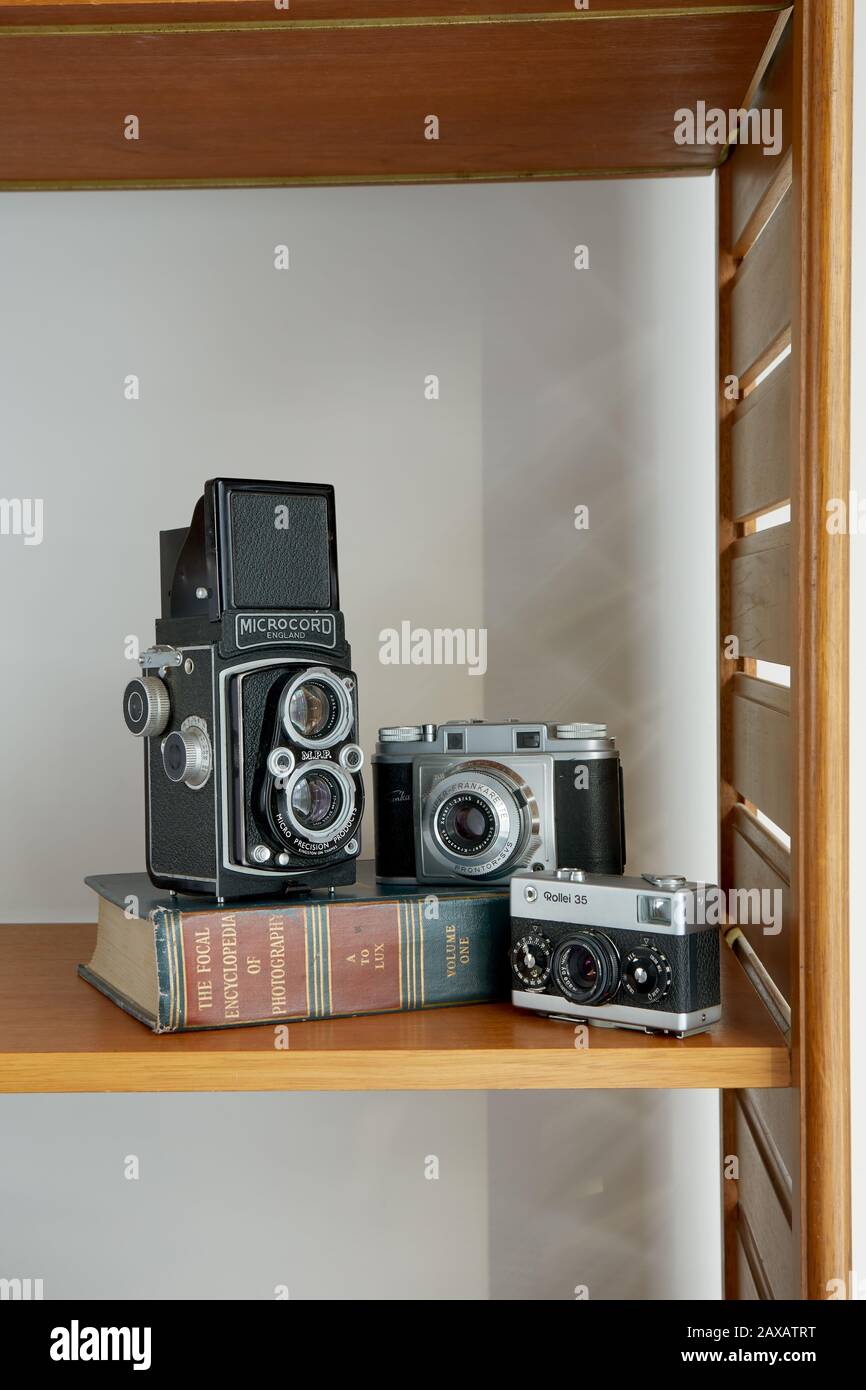 Ein Foto von drei Vintage-Kameras und ein Vintage-Fotobuch auf einem Regal. Stockfoto