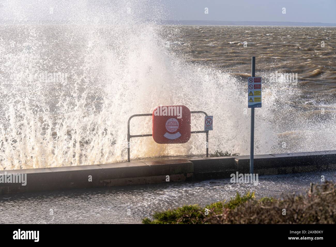 Wellen, die gegen die Meereswand an Der Leas, Westcliff on Sea, Southend, Essex, Großbritannien, krachen. Sturmflut Ciara. Rettungsgurt und Warnschild Stockfoto