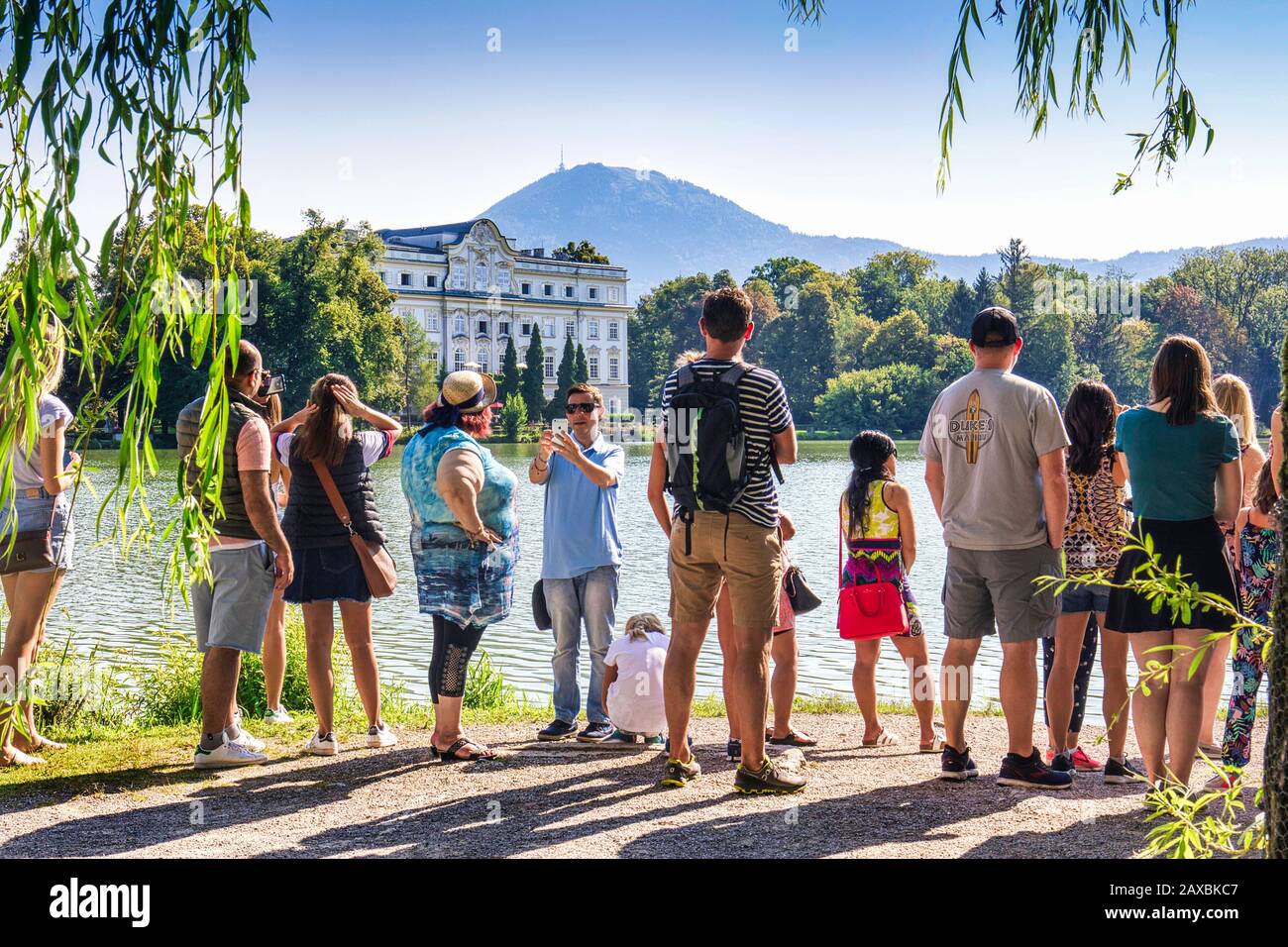 Touristen auf der Sound Of Music Tour. Blick über den Lake Leopoldskron zum Schloss Leopoldskron, wo die berühmte Bootsszene gedreht wurde. Salzburg, Österreich Stockfoto