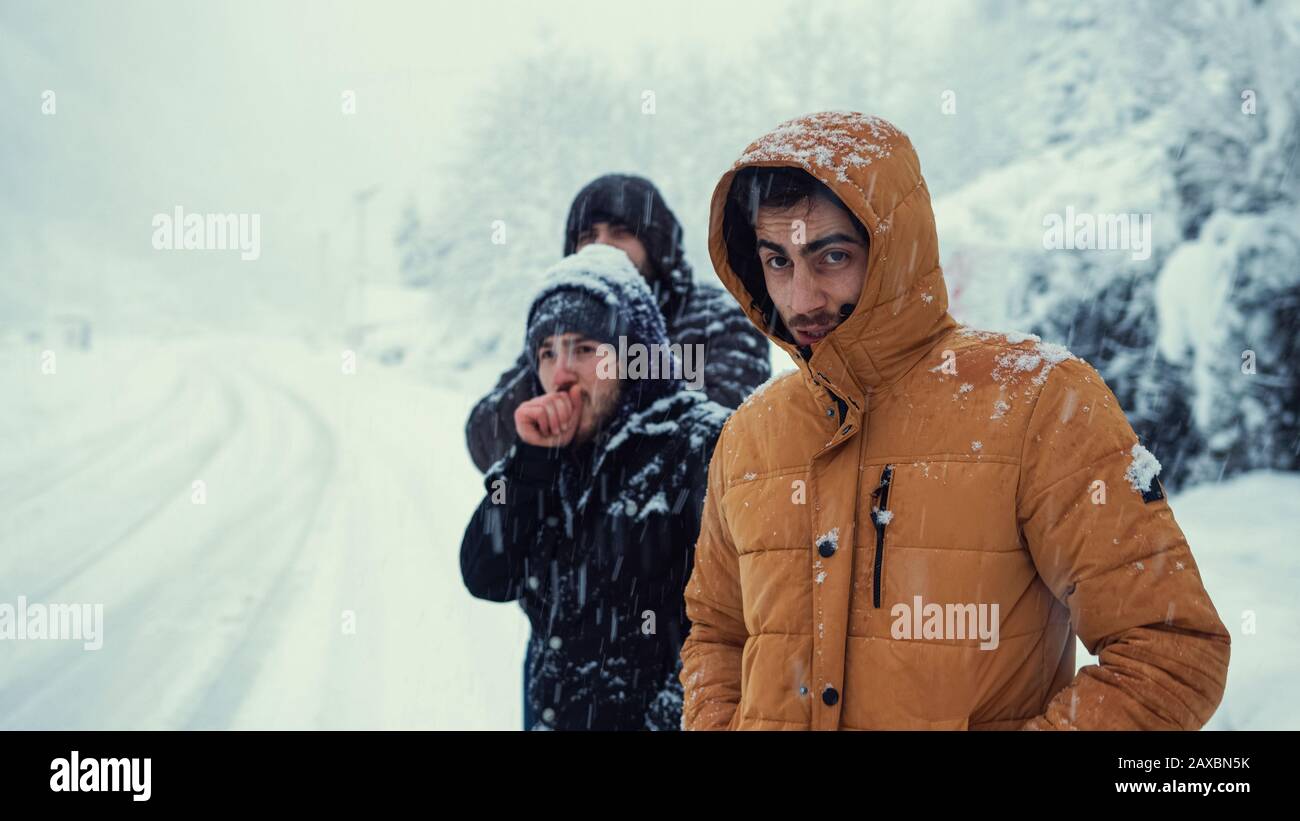 Die kalten Männer warten auf den Bus, während er an einem Wintertag schneit. Transportkonzept im Winter. Stockfoto