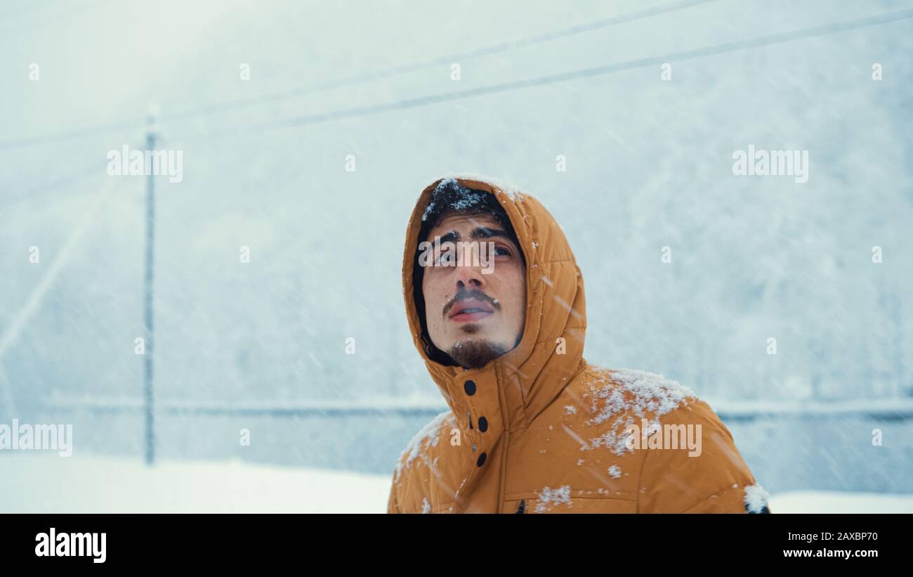 Porträt eines kalten Mannes, der einen Mantel trug, der im Schnee bei der Kälte Schnee gefangen hatte. Winterkonzept. Stockfoto